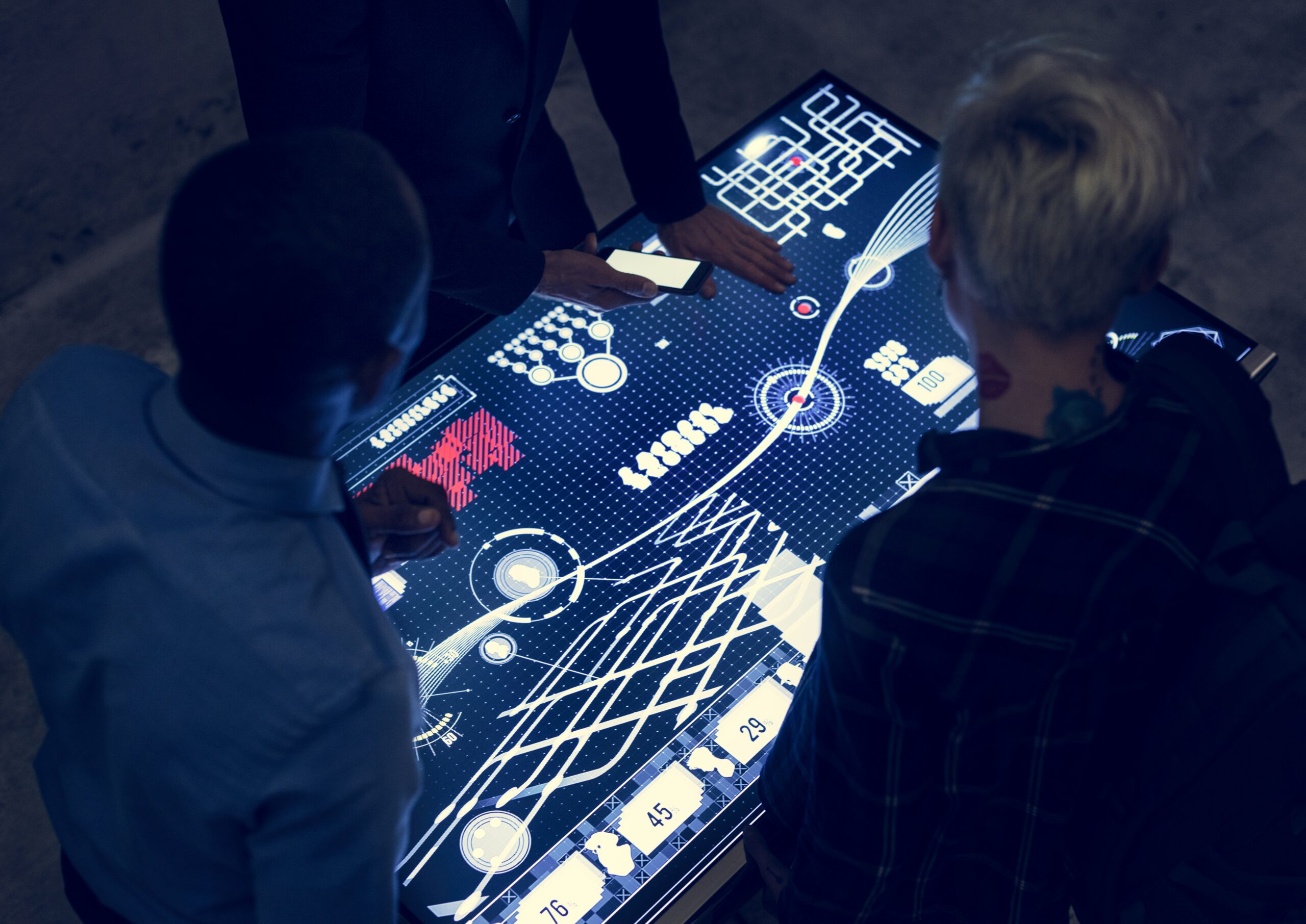 Team analyzing interconnected data streams and predictive models on a futuristic digital interface, illustrating AI simulation and intelligent business decision-making.